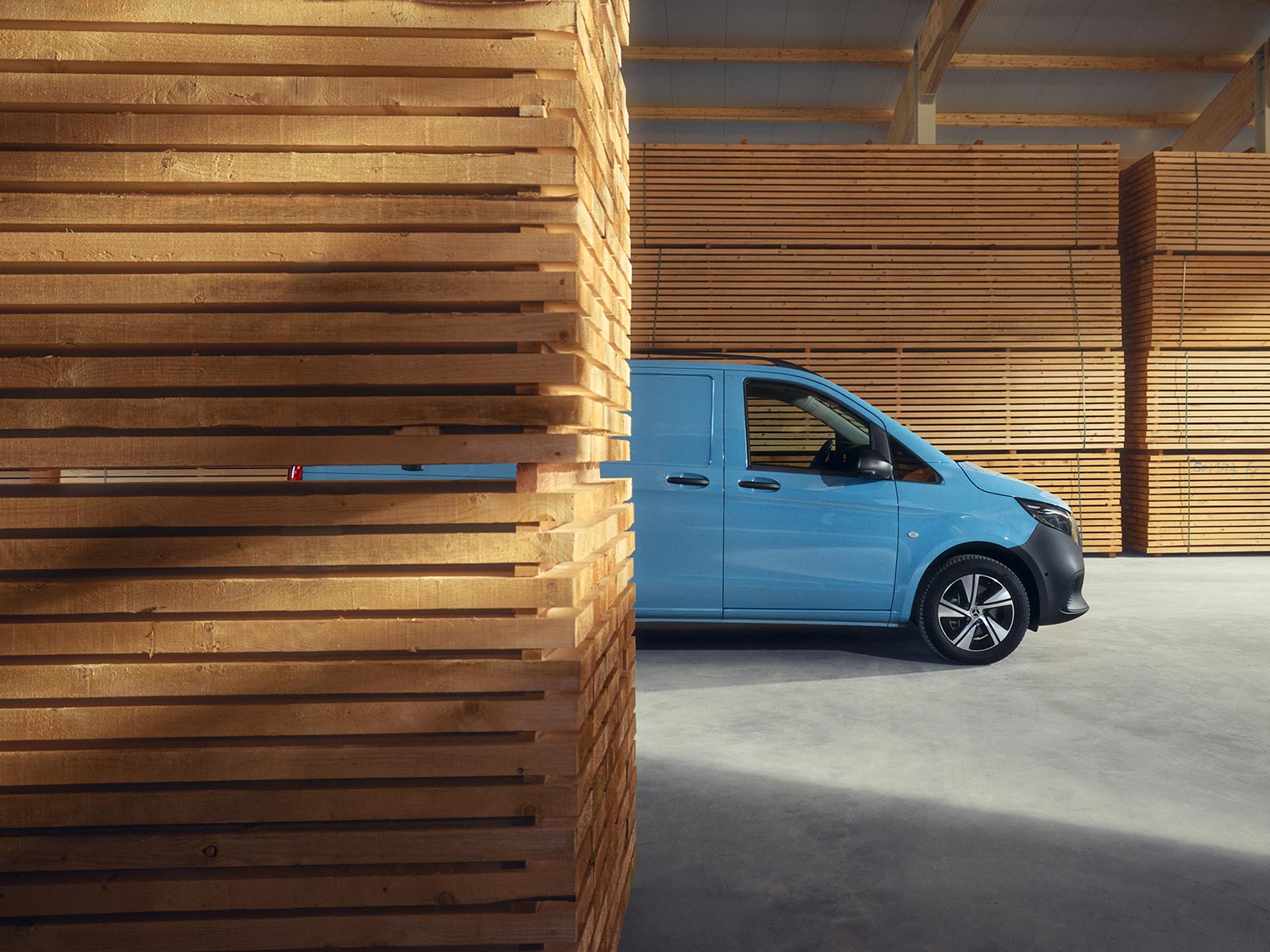 Mercedes-Benz Vito Błękitny Vito Mercedes-Benz zaparkowany pomiędzy deskami na terenie tartaku.