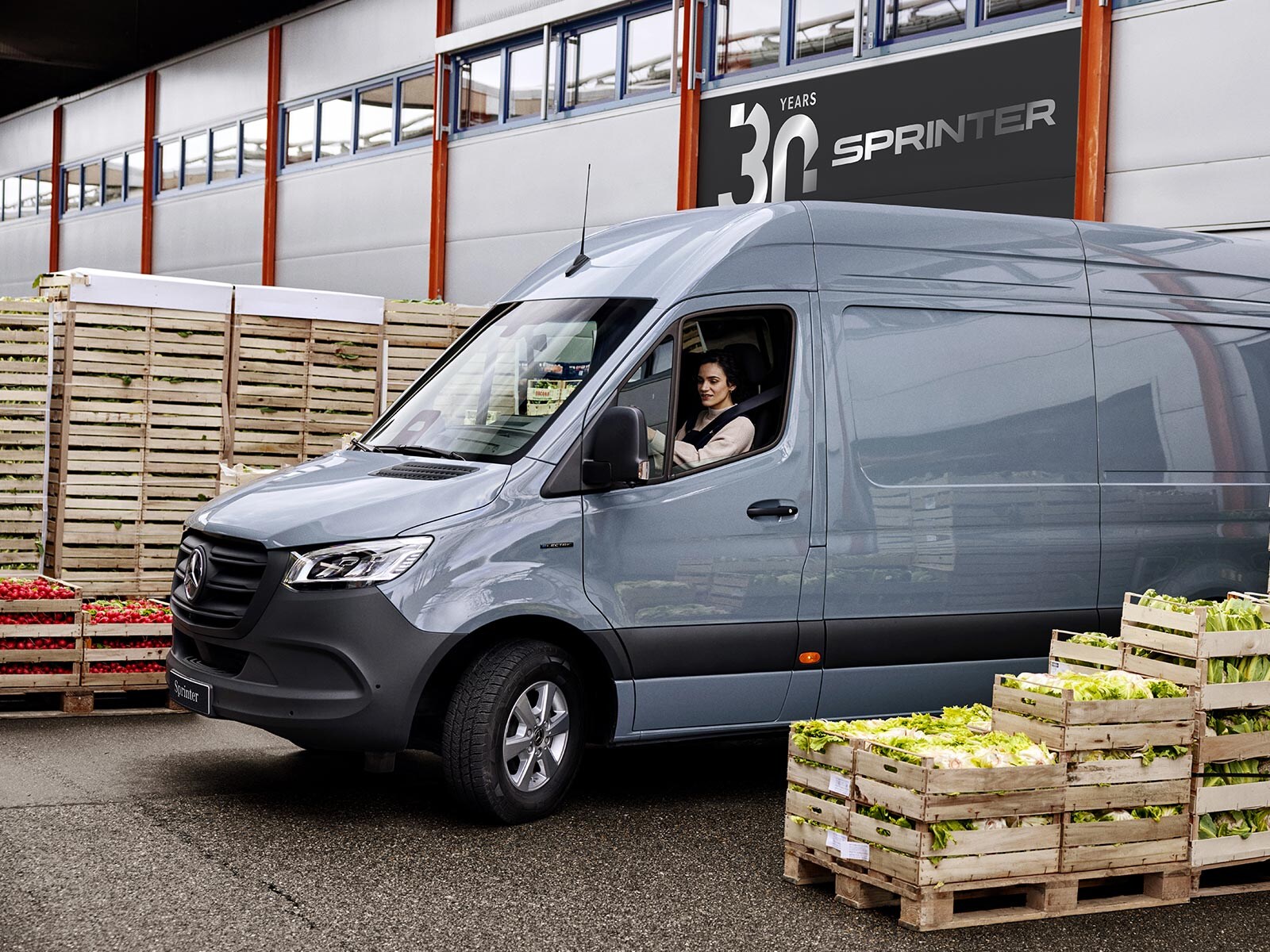 Szary Mercedes-Benz Sprinter podczas manewrowania między skrzynkami z warzywami.
