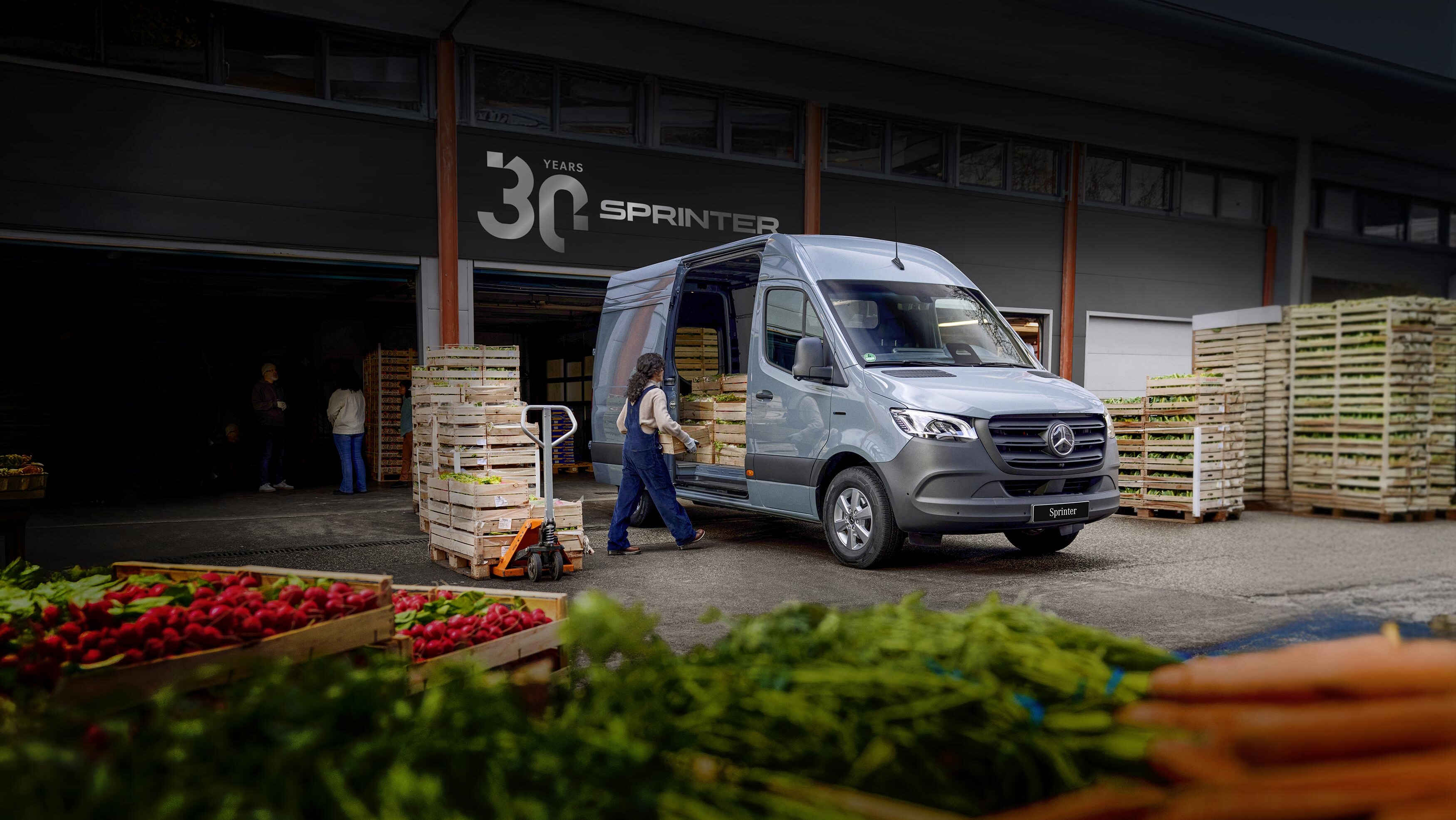 Szary Mercedes-Benz Sprinter podczas załadunku skrzynek z warzywami.