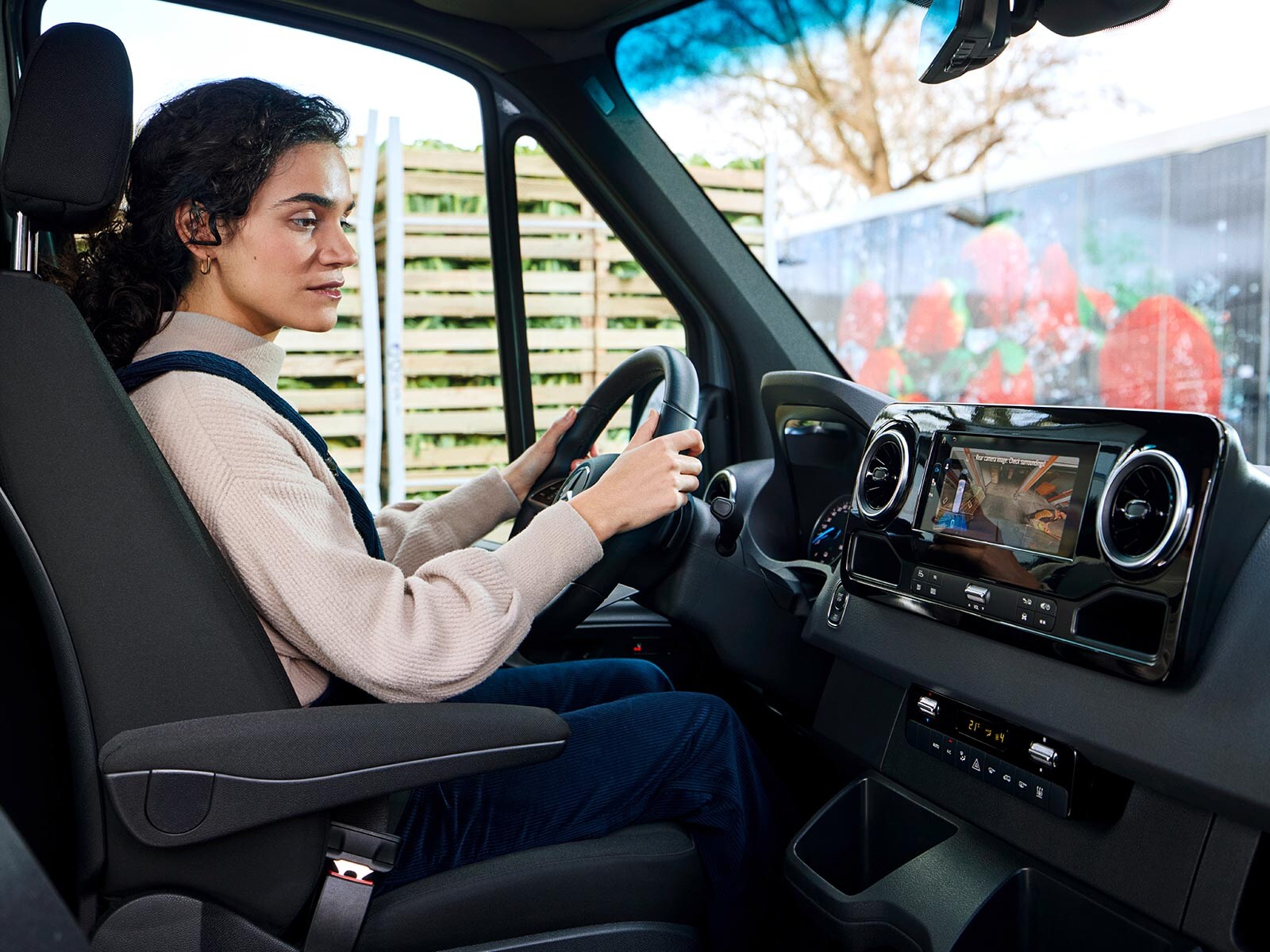 Kobieta parkuje Sprinterem z pomocą kamery cofania.