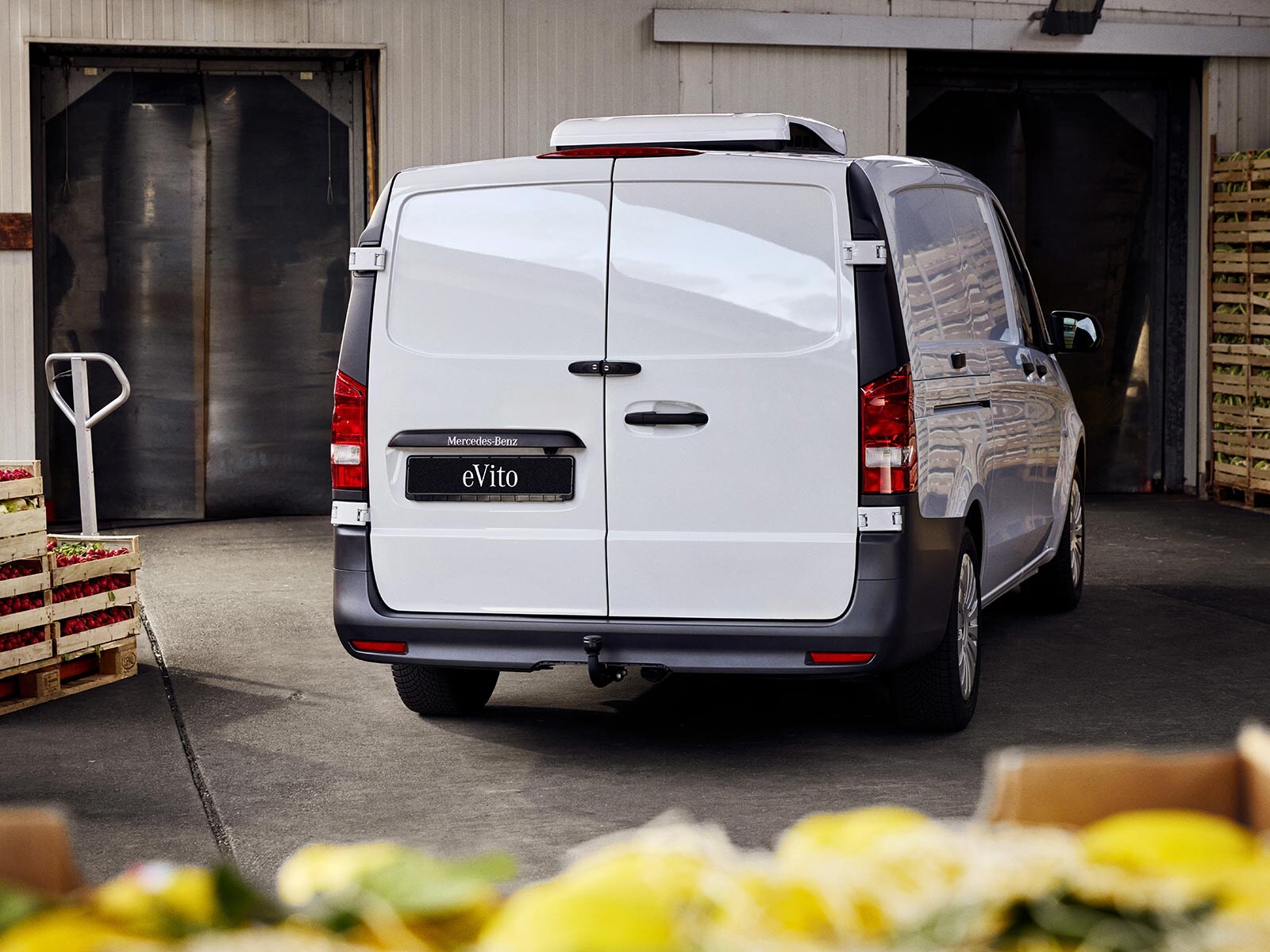 Biały Mercedes-Benz Vito podczas załadunku pojemników z kwiatami.
