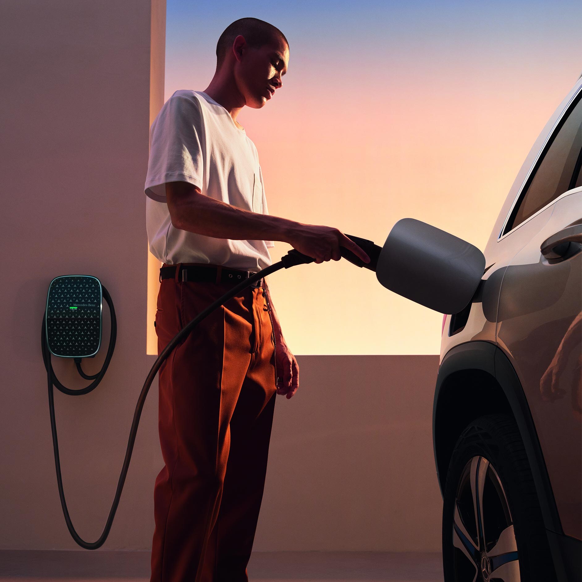 Mężczyzna podłącza swojego Mercedesa do stacji ładowania Mercedes-Benz Wallbox.