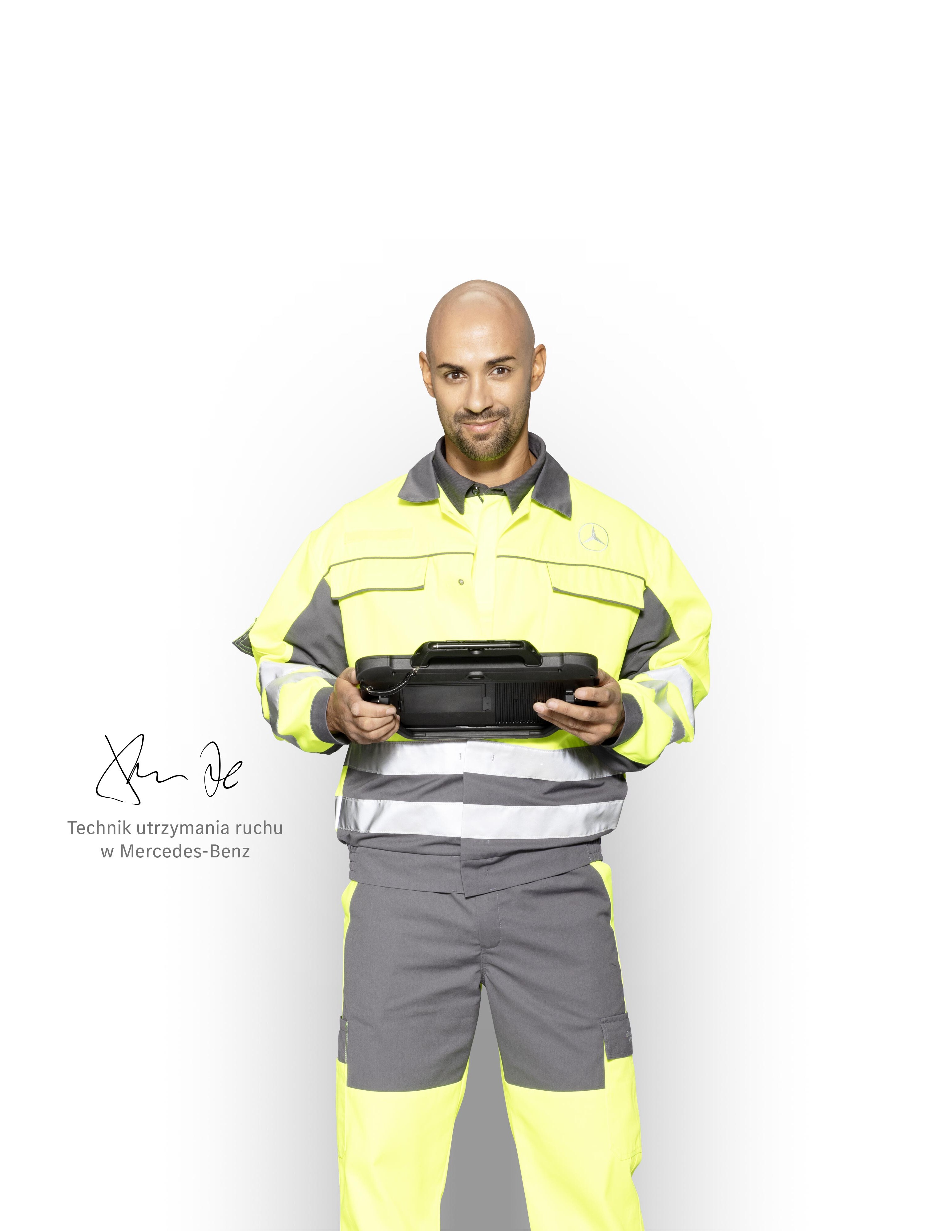 Technik serwisowy w odzieży roboczej z tabletem w ręku.