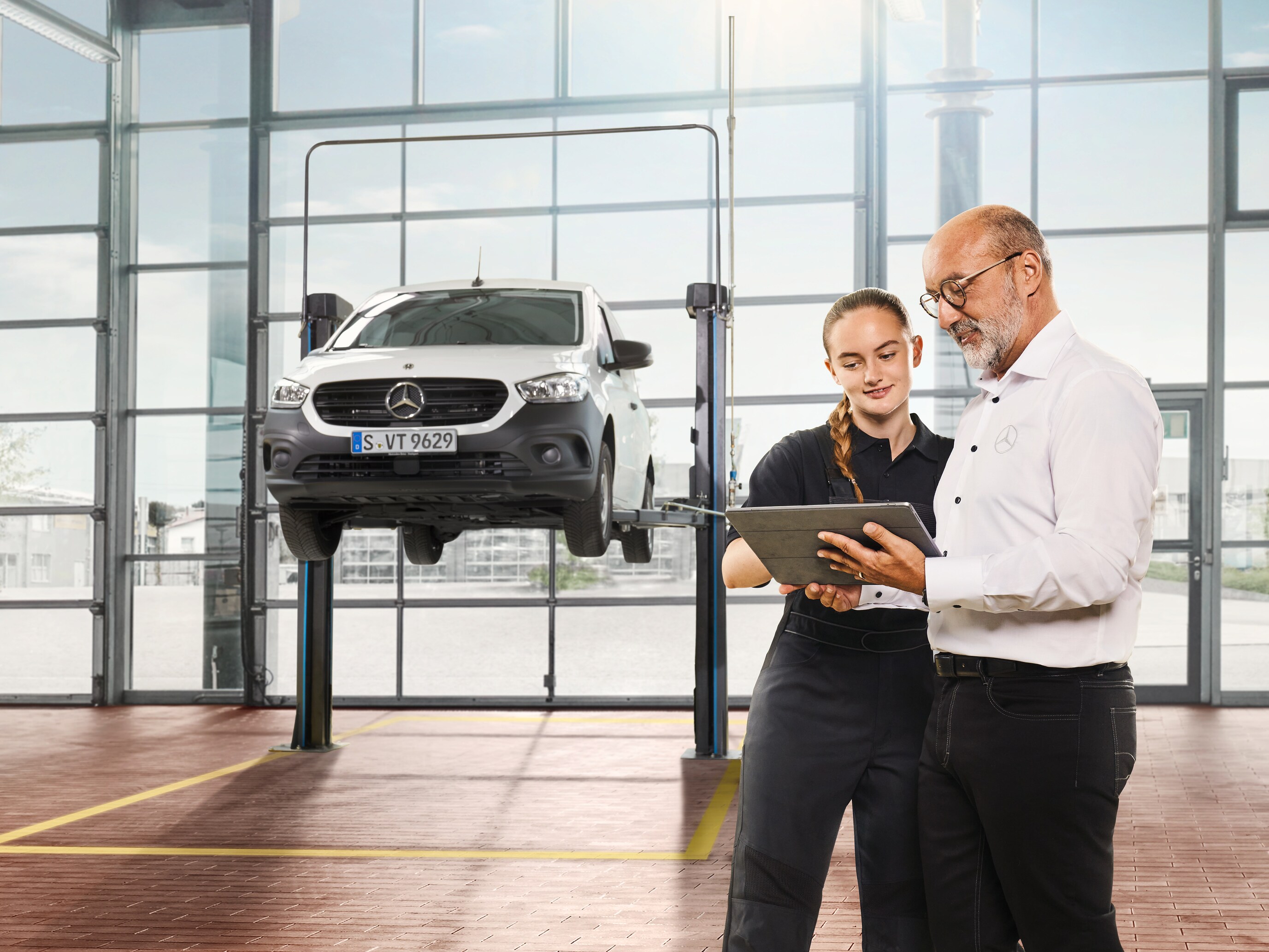 Pracownik serwisu rozmawia z klientem obok białego Citana Mercedes-Benz.