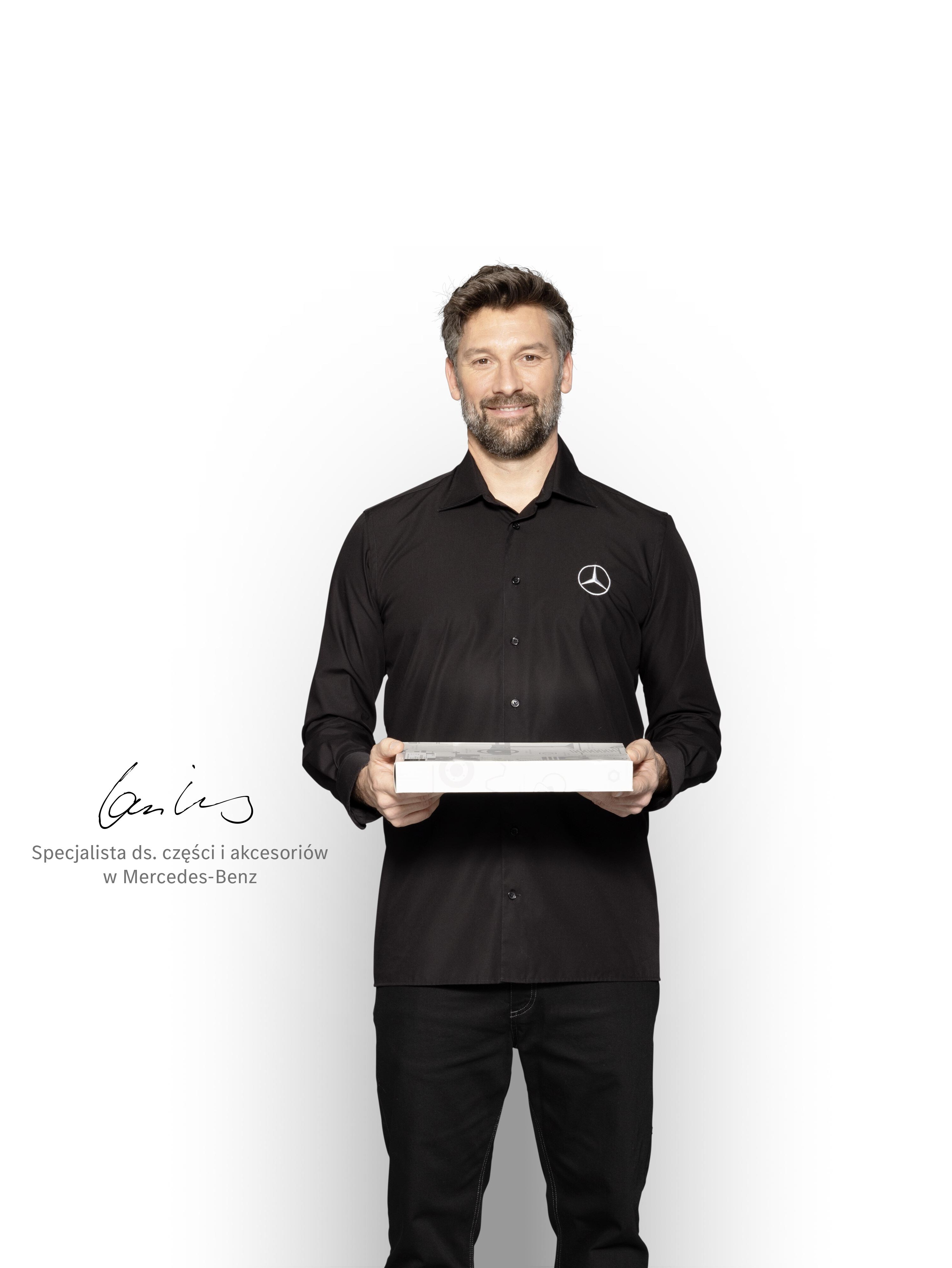 Technik Mercedes-Benz z pudełkiem w rękach pokazujący Oryginalne Części Mercedes-Benz.