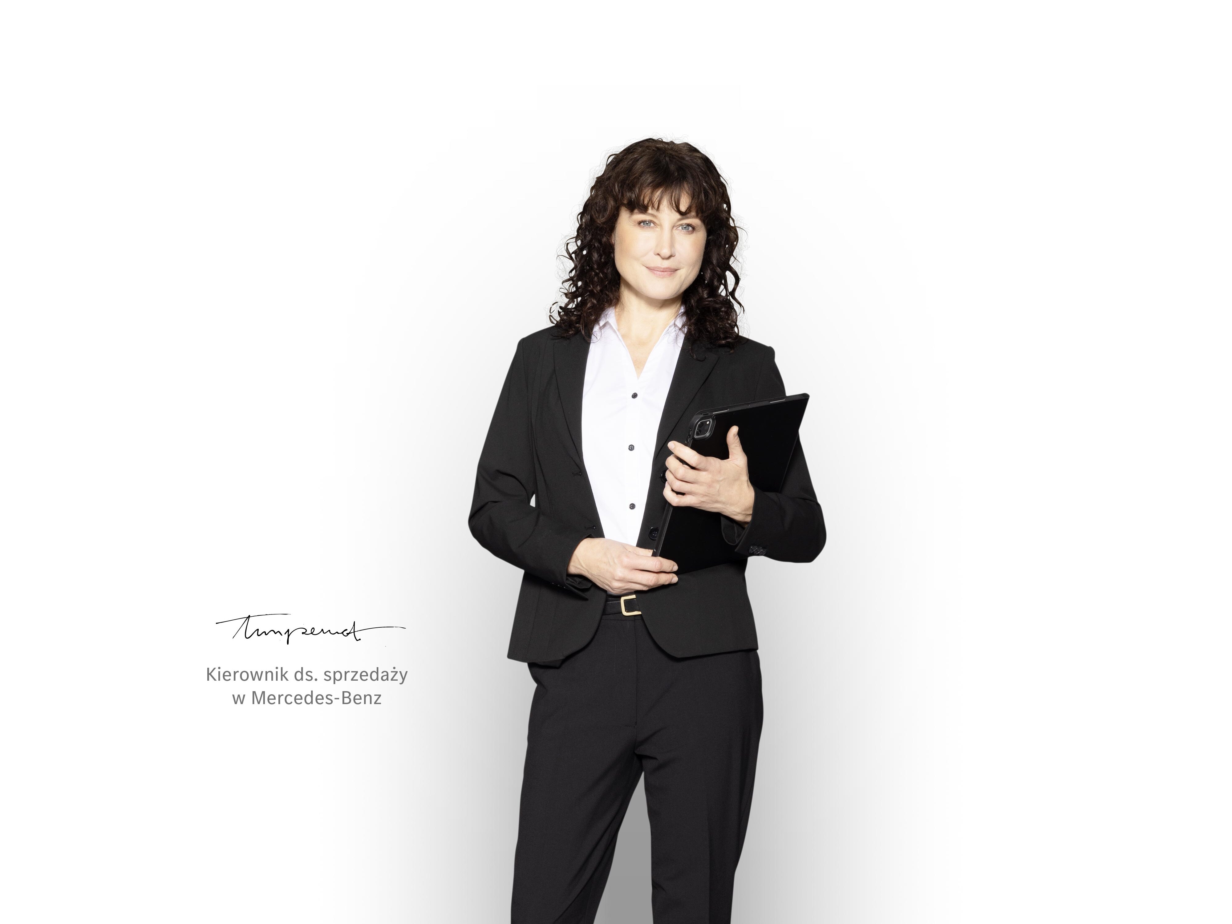 Kierownik ds. sprzedaży Mercedes-Benz z tabletem w dłoniach, gotowy do udzielania informacji na temat gwarancji na nowy pojazd.