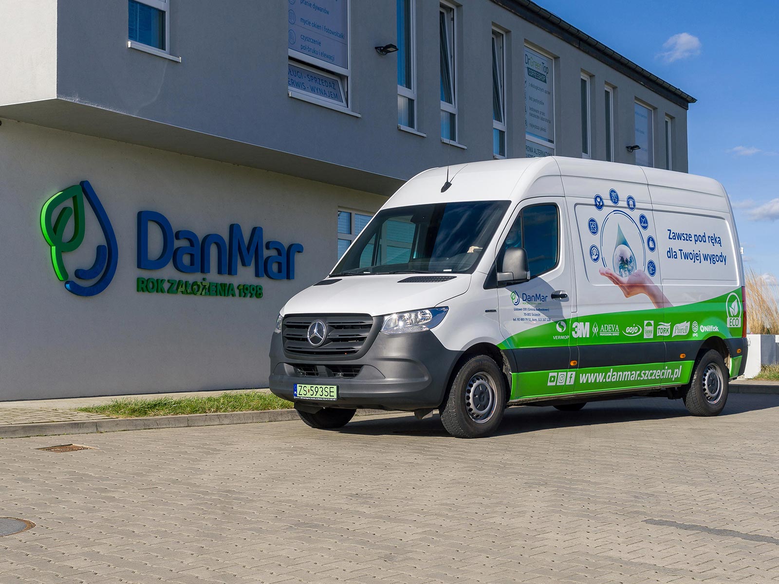 eSprinter w DanMar: ekologia jest sumą wielu elementów Biały Mercedes eSprinter na tle budynku z logo DanMar.