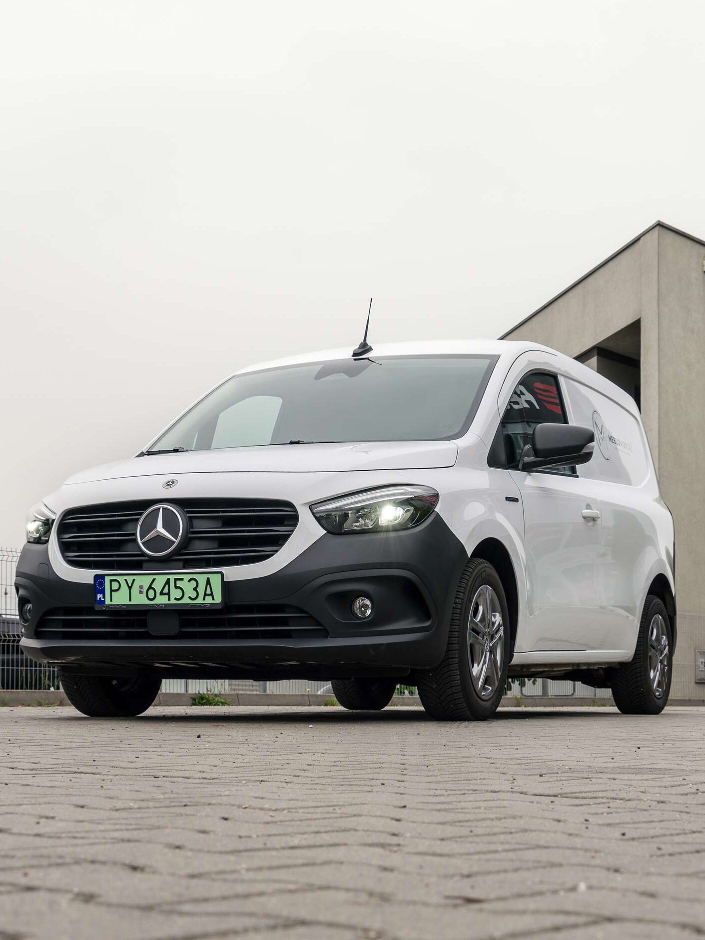 Biały eCitan Furgon przed budynkiem firmy Meblomontaż