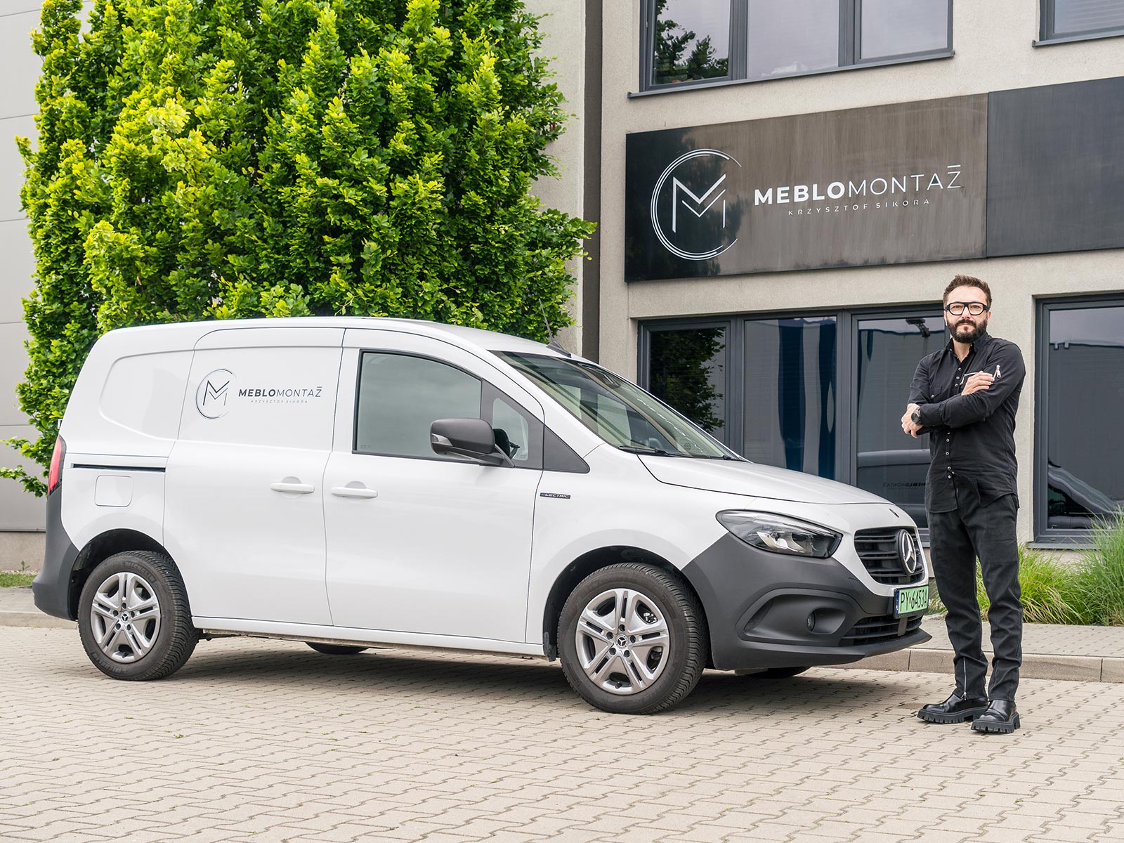 eCitany w firmie Meblomontaż Biały eCitan Furgon przed budynkiem firmy Meblomontaż.