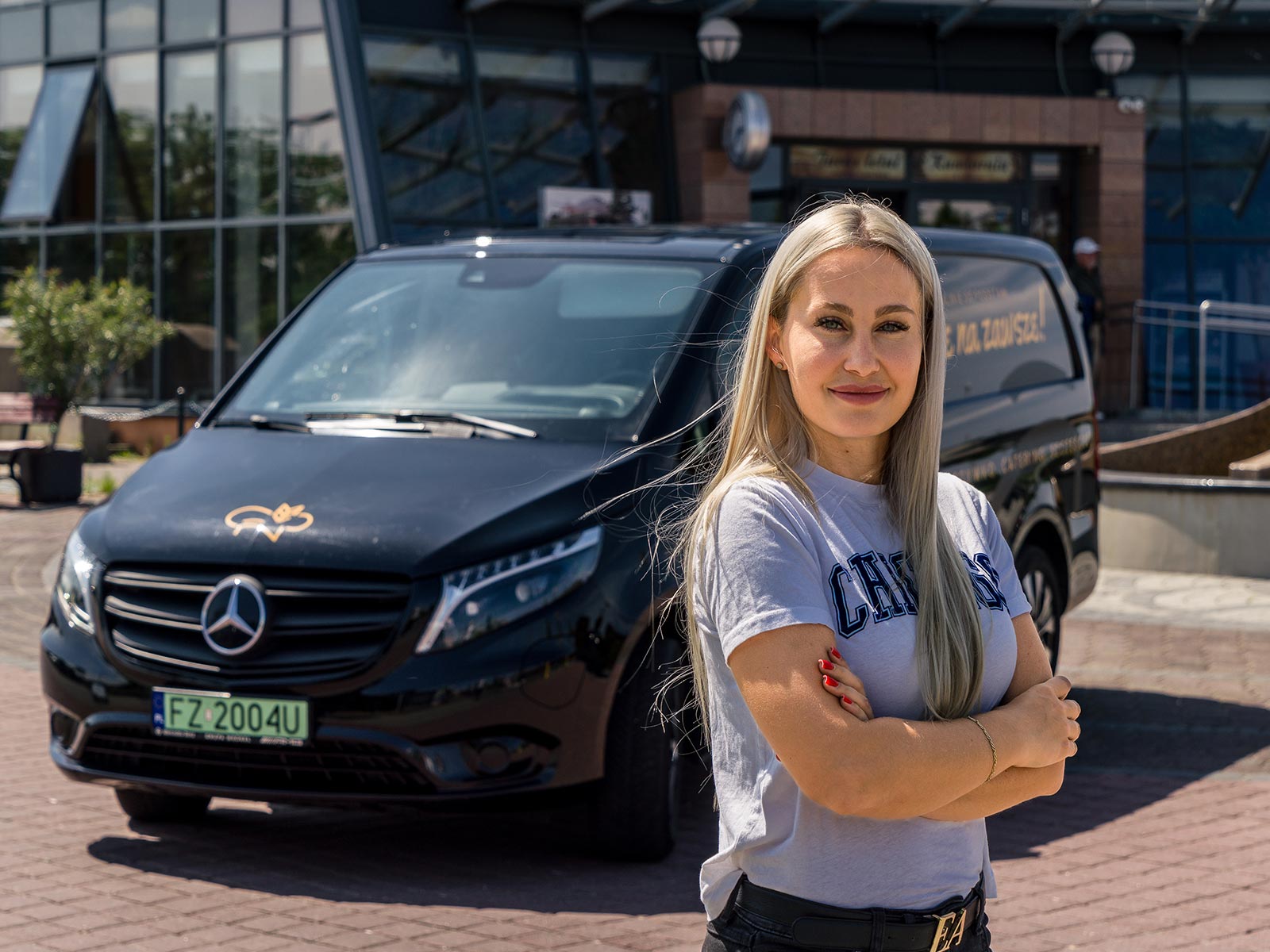 Pełną parą z pełną mocą Pracownik firmy Naturalnie Wyhodowane stoi przed czarnym Mercedesem eVito.