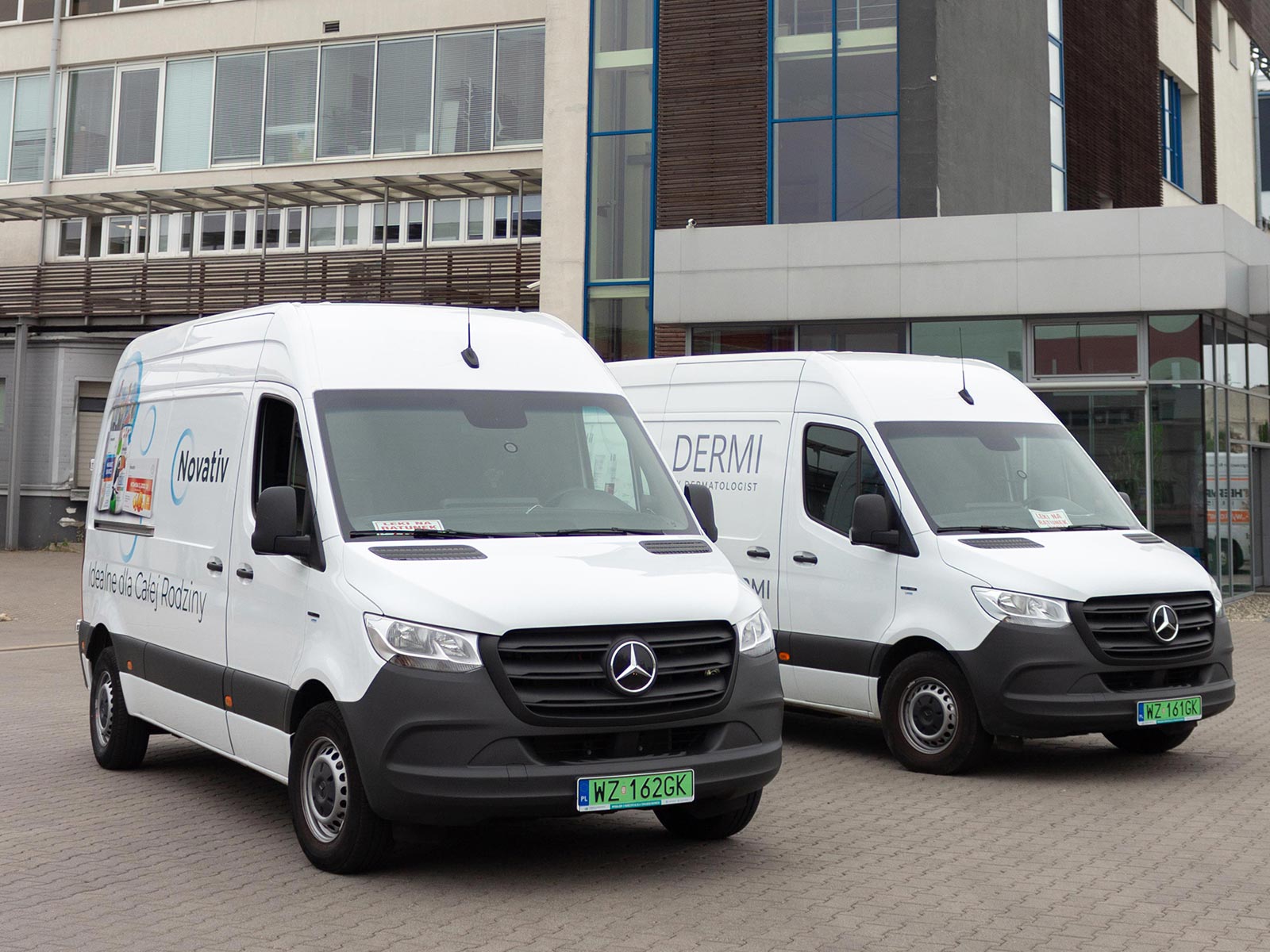Polska Grupa Farmaceutyczna przechodzi na elektromobilność z Mercedes Benz Vans Dwa białe Mercedesy eSprinter na tle budynku biurowego.