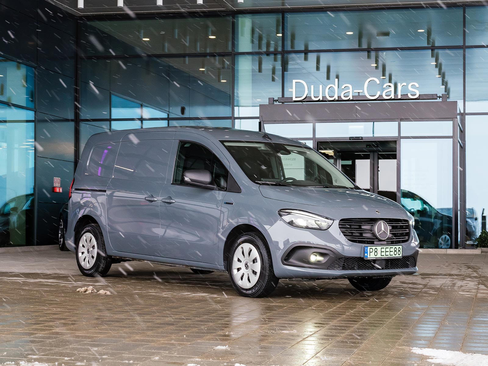 Szary Mercedes eCitan czeka na odbiór przez klienta przed salonem Mercedes-Benz Duda-Cars..